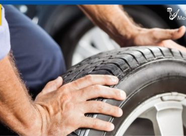 Imagen de neumáticos siendo sujetado por manos de mecánico, quien lleva a cabo el servicio de mantenimiento de neumáticos que necesitas para las vacaciones de verano